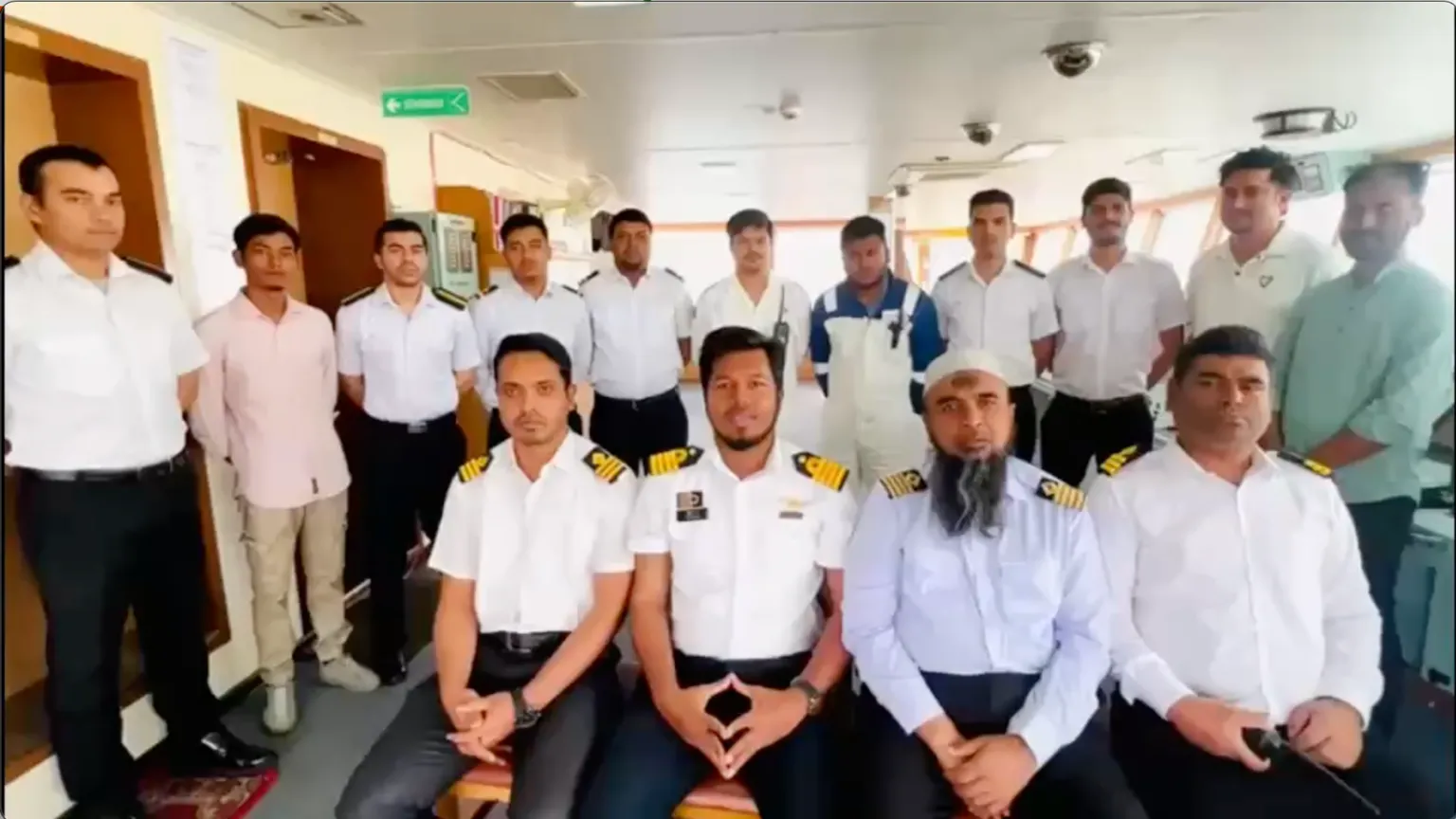 Captain Shafiqul Islam [second from right]and chief engineer Rashedul Hasan [sitting to the left of the captain] record morale -boosting video aboard the stranded Banglar Joyjatra in the Persian Gulf, June 3, 2026. Photo: Reuters
