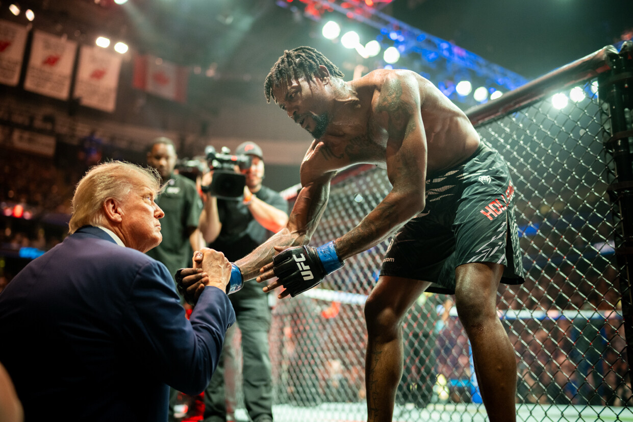 President Donald J. Trump shakes hands with a fighter across a cage barrier at a UFC event in Canada on 07/14/2026.