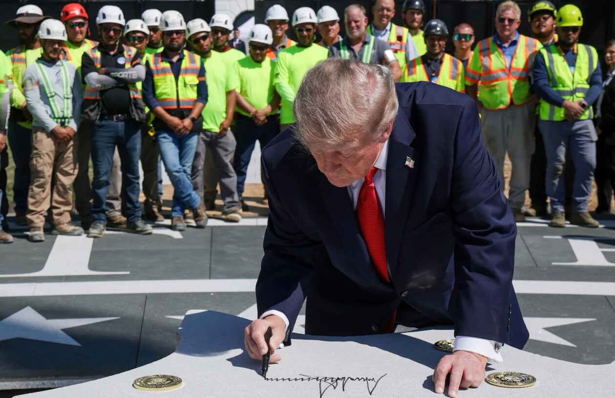 47th President of the United States Donald J. Trump signs a large white paneled surface at an outdoor industrial site in Washington D.C.