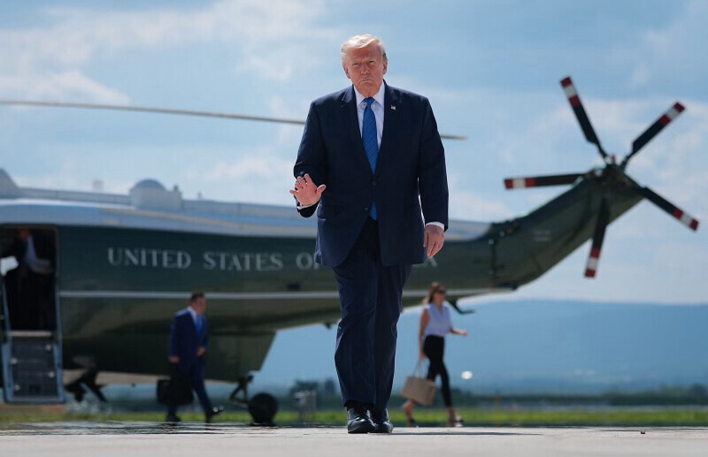 President Donald J. Trump walks past a military helicopter with "United States of America" visible on its fuselage on a tarmac in Washington D.C.